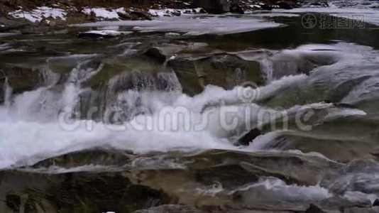 冬天，雪从山溪和石急流中快速流出的水。 瀑布。 慢动作视频