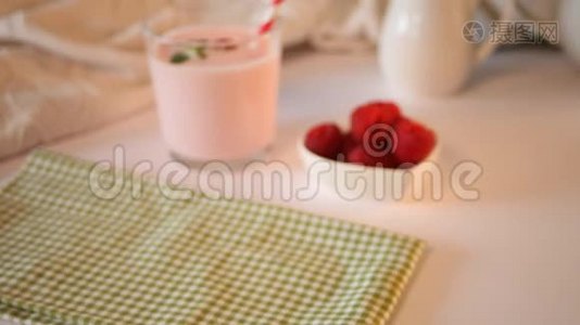 女人的手放在桌子上，玻璃杯里是天然自制的酸奶和新鲜的覆盆子。 早餐概念视频
