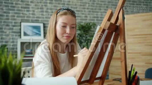 幸福的年轻女士坐在画架上用彩色铅笔在家画画画视频