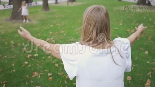 后景的年轻白种人妇女坐在公园里等待她的女儿拥抱。 可爱的小女孩在奔跑视频