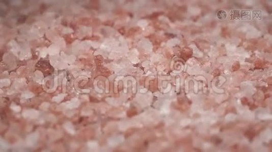 旋转喜玛拉雅盐的宏观镜头，并落在桌子上。 粉红色的盐很好吃，很好的香料。视频