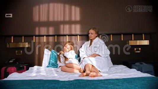 一家人在酒店房间里穿着白色浴袍-爸爸把茶杯带到床上给他的妻子和女儿视频