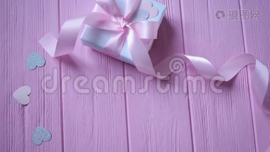 礼品盒与丝带和纸屑的形式，心在粉红色的木制背景与地方为您的文字。 录像播放视频