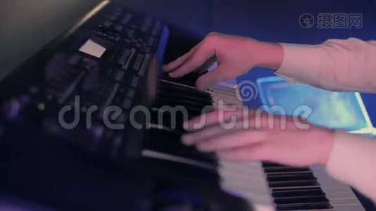 钢琴家的特写`他的手在蓝色灯光的舞台上用键盘弹奏一首歌视频