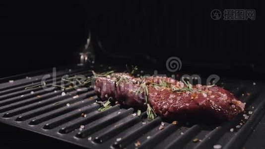 美味多汁的肉排在烤架上。 烹制优质鲜烤. 把牛肉扔到电烤炉上。 倒入盐，迷迭香视频