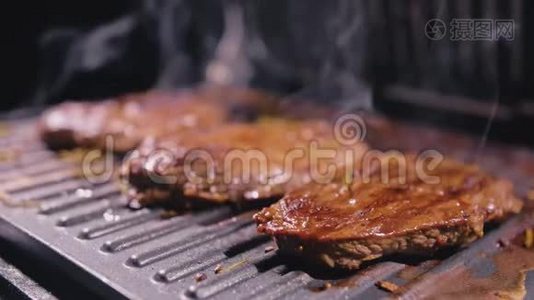 美味多汁的肉排在烤架上烹饪。 电烤炉上的优质牛肉，迷迭香，黑胡椒，盐。 慢慢视频