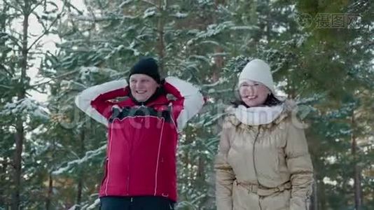 欢快的情侣在冬日的森林里笑着雪树上的风景。 快乐的男人和女人在雪地森林里玩得开心视频