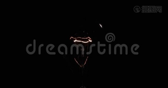 一个旧灯泡的闪光螺旋。 黑色背景上的钨丝。视频