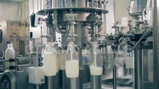 透明的瓶子被工厂的综合体装满了牛奶。 工业工厂设备视频