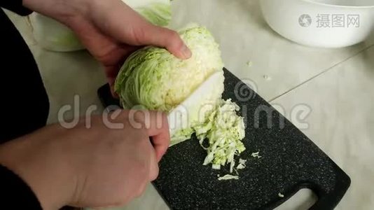 女人用刀子在木板上切一棵绿色的卷心菜。 把切菜的刀切成沙拉。 食物视频