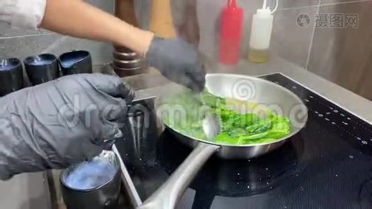 厨师在金属锅上菜，搅动菠菜叶子视频