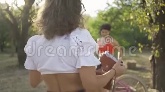 可爱的白种人年轻女性，留着短发，在她的朋友在花园或公园拍照时，用自行车摆姿势视频