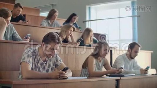 大量的学生看着智能手机的屏幕，在现实生活中不交流，只写信息视频