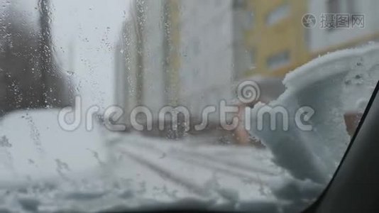 一块雪落在汽车的挡风玻璃上. 汽车雨刷开始清洗玻璃。视频