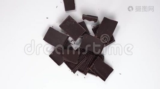 打开的巧克力片的俯视图。 黑巧克力旋转，旋转在白色的桌子上。 甜点在桌子上。视频
