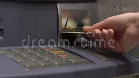 一位年轻妇女把一张银行卡插入ATM机。 提款机用于现金取款和存款。 女`的手特写..视频