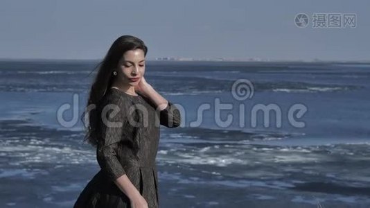 一个穿着黑色裙子的小女孩在阳光明媚的大海中抚摸着她的头发视频
