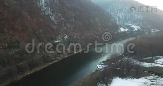 一架无人机沿着雪岸上的一条冬天的河流飞行。视频