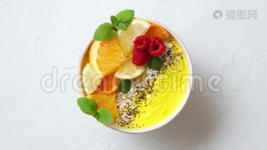 美味的橙色新鲜冰沙或酸奶在碗里。带着覆盆子，橘子片，辣椒籽视频