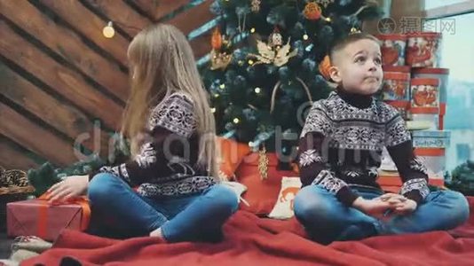 可爱的4k视频妹妹送圣诞礼物盒给她的哥哥，坐在树旁，在圣诞节设计视频