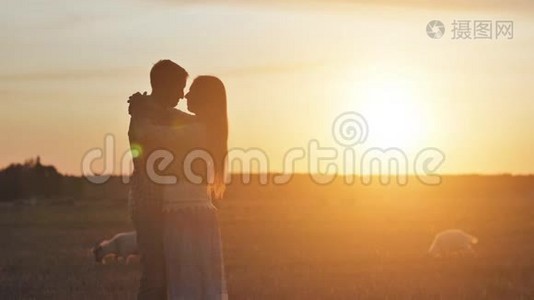 情侣在日落和山羊背景下拥抱情侣的剪影。视频