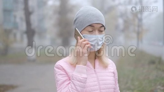 冠状病毒保护。 一位戴着医用防护面罩的年轻女性站在欧洲的一条城市街道上，手里拿着智能手机。视频