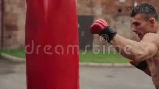 近距离观看穿红色手套的男拳击手在户外打红色拳击袋视频