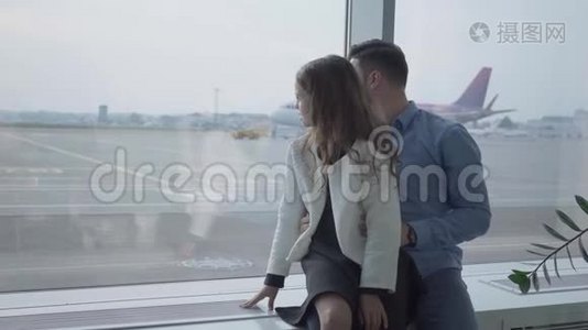 成年白人男子和他的女儿坐在机场窗台上看着跑道。 小可爱视频