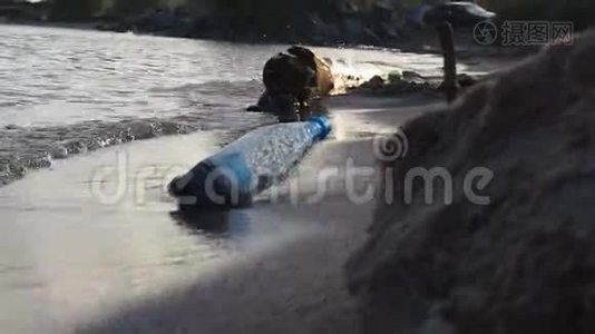一个塑料瓶躺在海滩上。 波浪在上面冲刷。 防治环境污染的概念视频