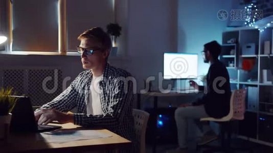 一个同事在黑暗的办公室里工作时用手提电脑打字的家伙视频