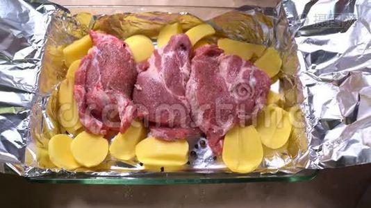 在生土豆和猪肉脖子上放洋葱切环。视频