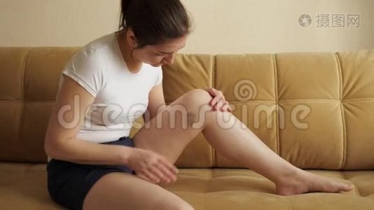 坐在沙发上的女人检查她腿上的伤视频
