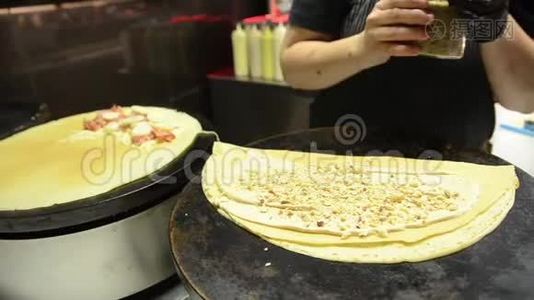 女人在热电炉上做煎饼。 在街上准备美味可口的食物。 厚薄饼。 女孩准备视频