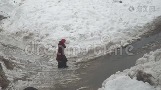 女人穿过水坑和潮湿的雪视频