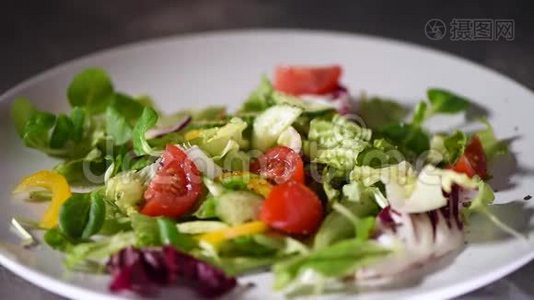 蔬菜沙拉配青菜，黄瓜，西红柿，胡椒粉的制作.. 混合掉在石盘上的绿色沙拉。 顶级视频