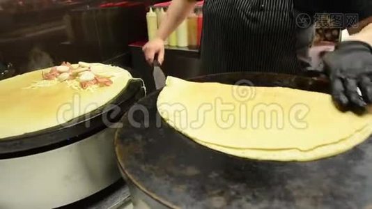 女人在热电炉上做煎饼。 在街上准备美味可口的食物。 厚薄饼。 女孩准备视频