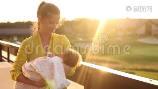 一组视频：穿着黄色上衣的女人用粉红色毯子把她的小婴儿轻轻地抚摸起来视频