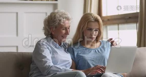 年长的母亲和成年的女儿使用笔记本电脑看屏幕视频