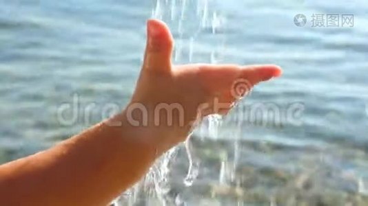 宝贝`在海景背景上的手抓水滴。 幼儿`手玩水.. 健康儿童概念视频