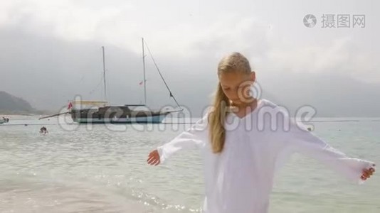 可爱的少女穿着白色长袍，在船上欣赏大海的风景。 站在山上避暑的旅游女孩视频