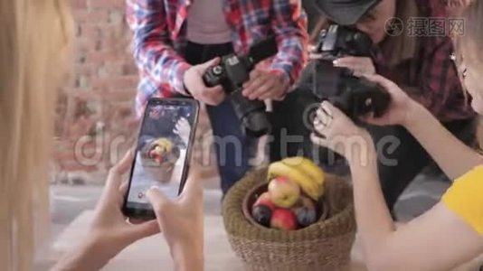 现代的经营者使用照相机和手机在主人的餐桌上拍摄篮子里的水果视频