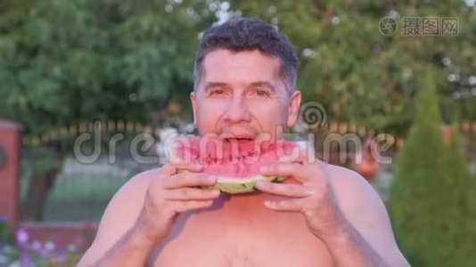 英俊的中年人在户外吃一个多汁的西瓜。视频