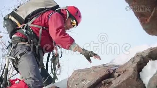 一个穿着红色西装和装备的登山者跪着靠在冰斧上爬山视频