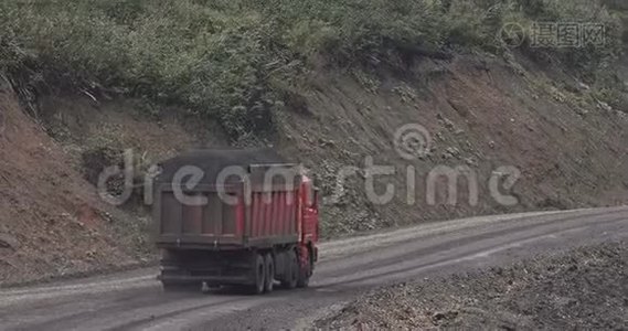 卡车的航空测量。 倾斜覆盖的自卸汽车沿着乡村道路运输煤炭。 卡车在肮脏的乡村行驶视频