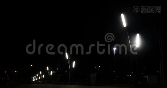 黑暗的夜晚街道上的公共灯和背景上经过的汽车。视频