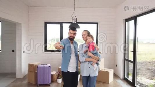 年轻的一家人刚搬进一个新家，爸爸在一个新家里自拍他的家人视频