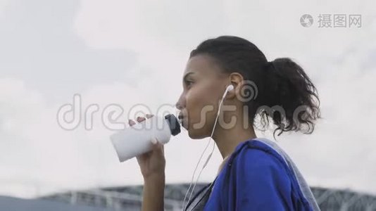 非洲裔美国跑步妇女跑步后饮水或等渗。 肖像健身妇女饮水瓶。视频