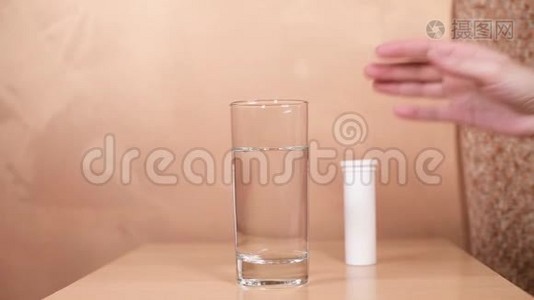 女孩的手随便地把两个放进一杯水里，放在桌子上。视频