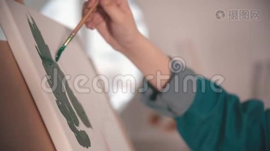 一位年轻女子在艺术工作室的画布上`一幅绿色的手画视频