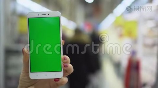 Pov，女性手提智能手机，带着空白绿色屏幕，在购物中心散步视频